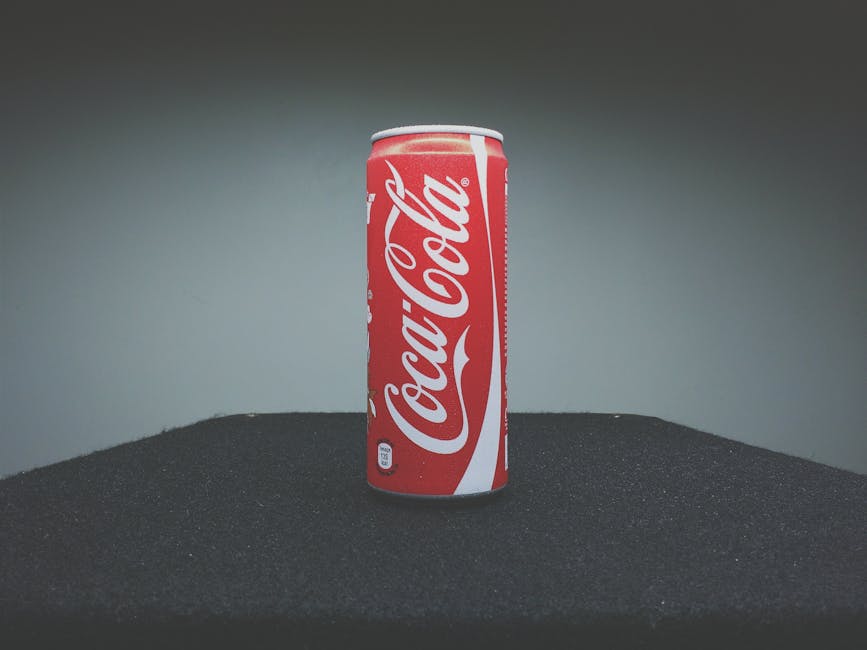 A classic Coca-Cola can showcased on a dark surface with minimal lighting.