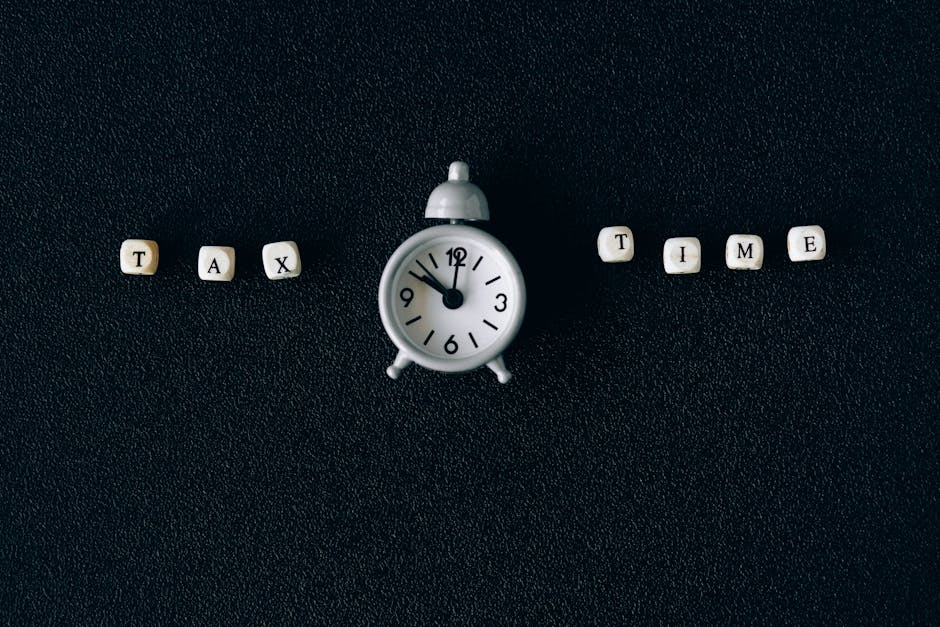 Conceptual image of tax time with clock and letter blocks on black background.